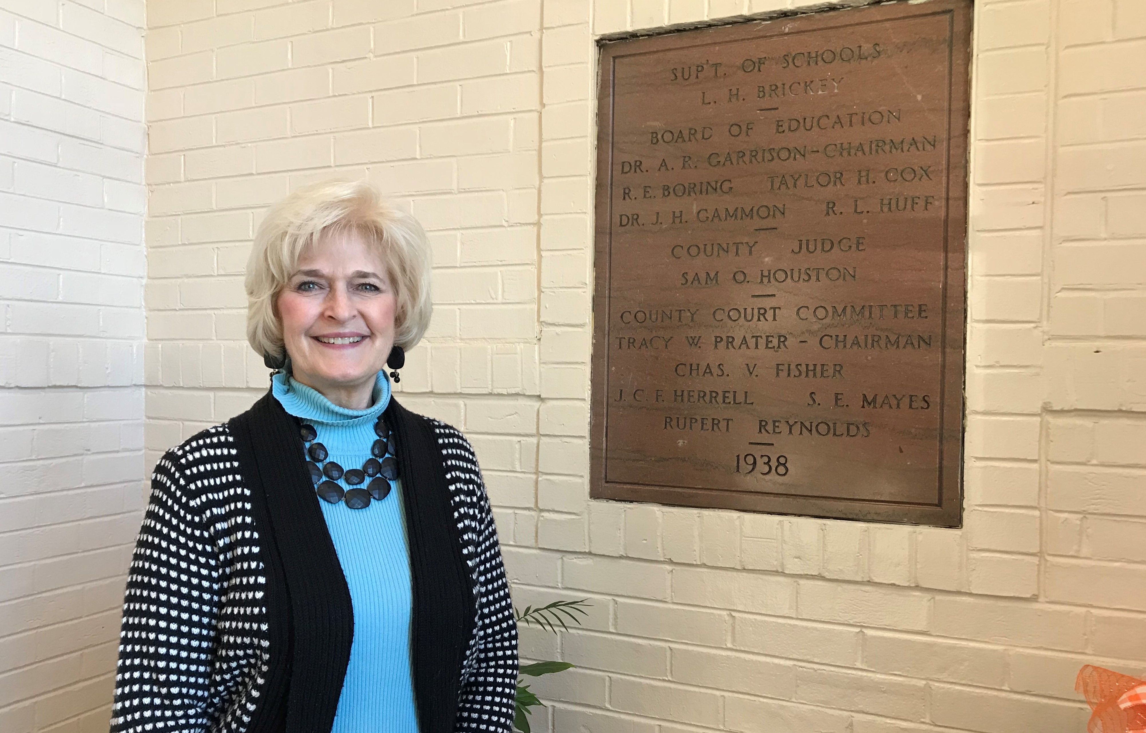 Susan Dunlap, Principal of Bearden Elementary School, stands next to a sign commemorating the school's opening in 1938. 