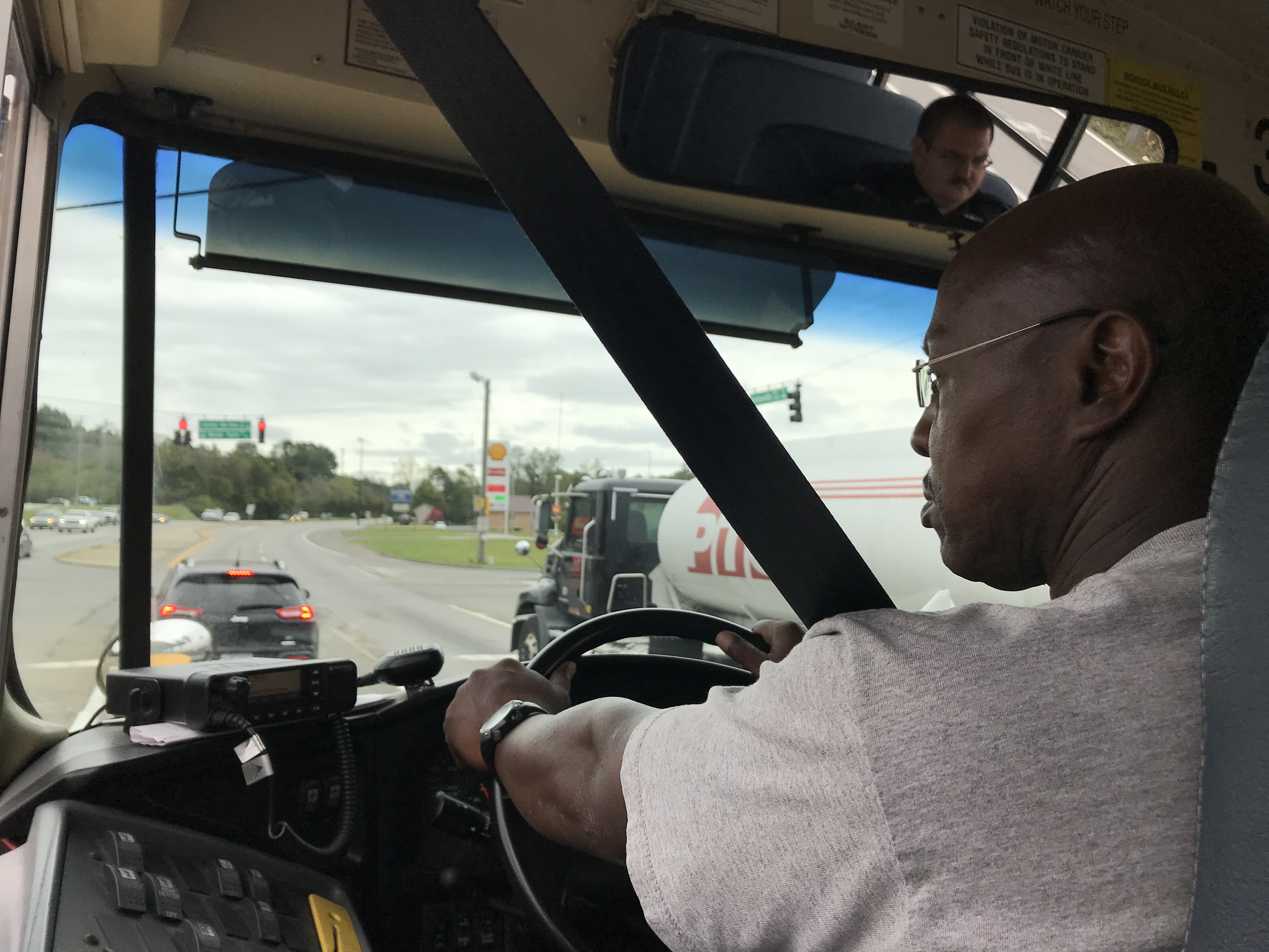 Lynch Bus Lines driver Terry Holloway sits in the driver's seat during a check ride on October 16, 2018. Benjamin Honaker, of the Knox County Schools Security Division, is pictured in the rearview mirror. 