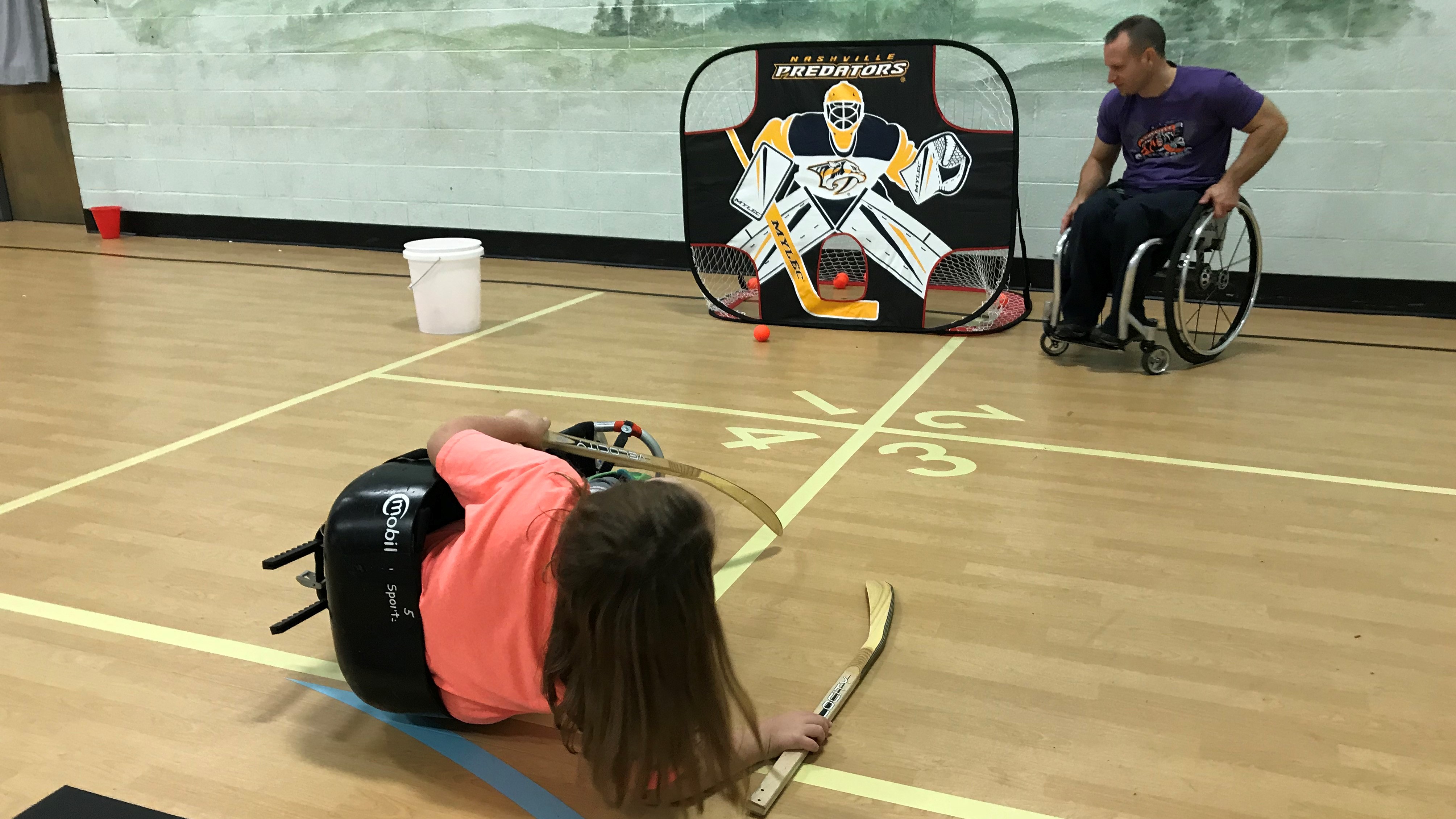 A Ritta Elementary student tips over while working with Matthew Porterfield, of the Knoxville Sled Bears, on a shooting drill. 