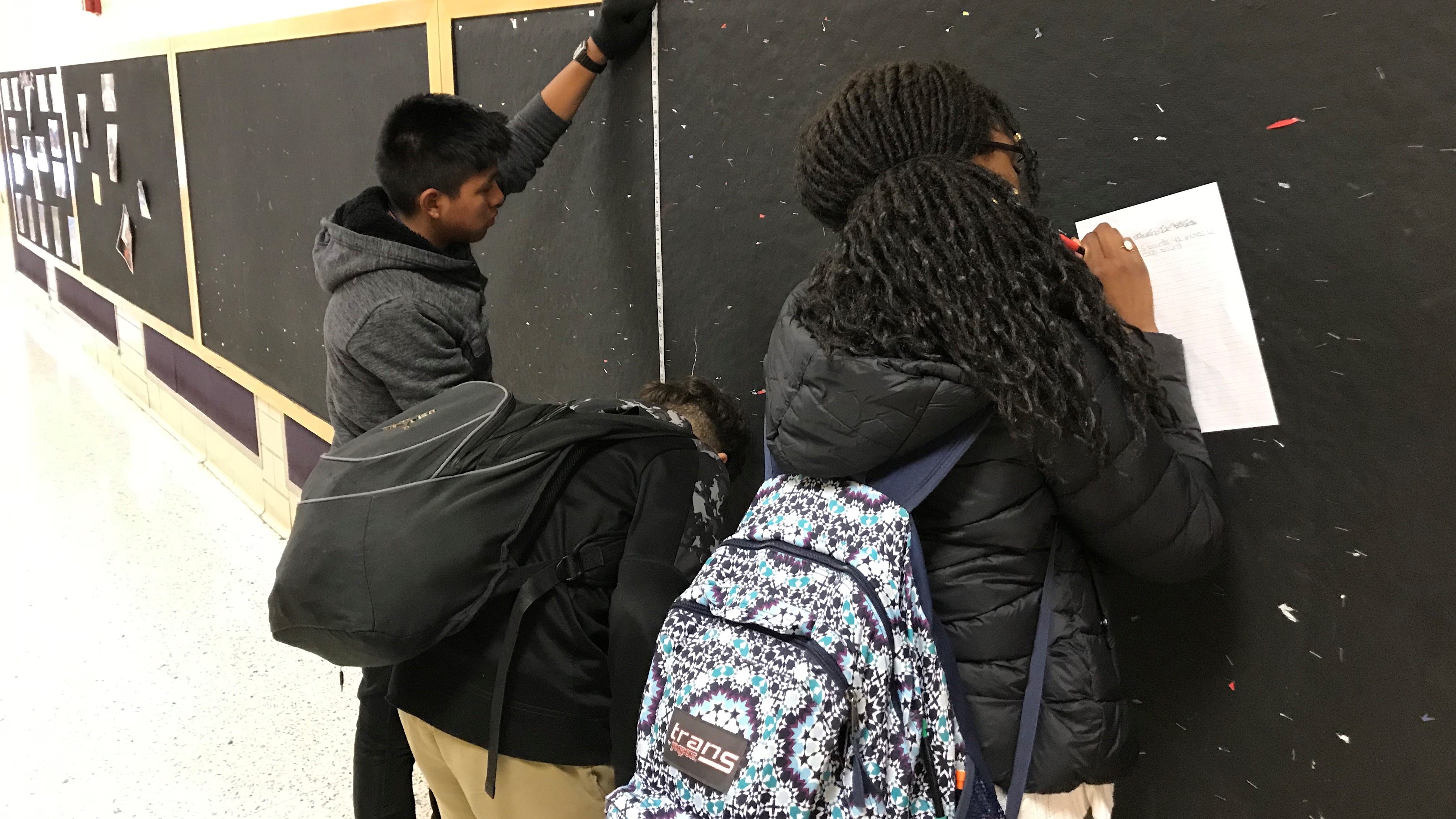 Students at Vine Middle School measure a hallway bulletin board, as part of a project to add inspirational quotes and new artwork in the hallways. 