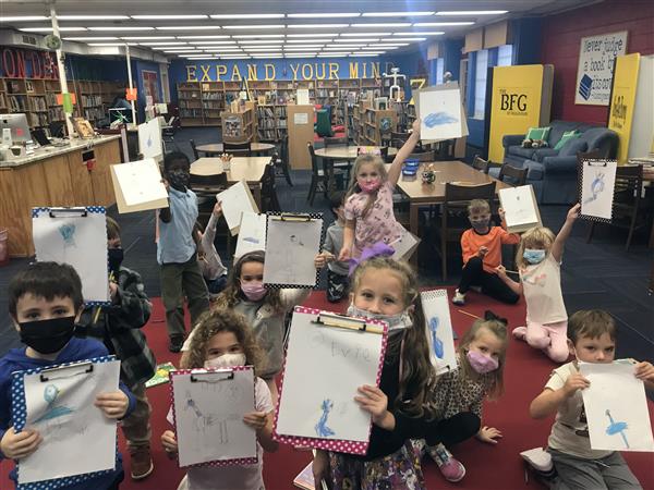 A class holds up drawings of a blue pigeon